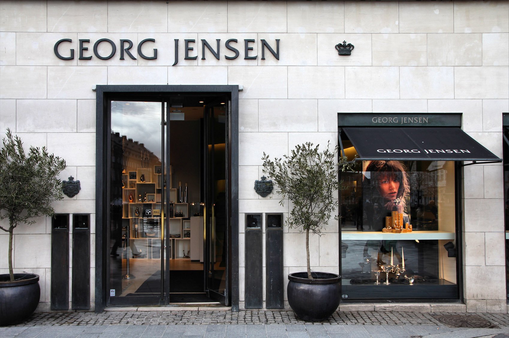 Außenansicht eines Georg-Jensen-Geschäfts mit einem großen Schaufenster und einer Markenbeschriftung über dem Eingang.